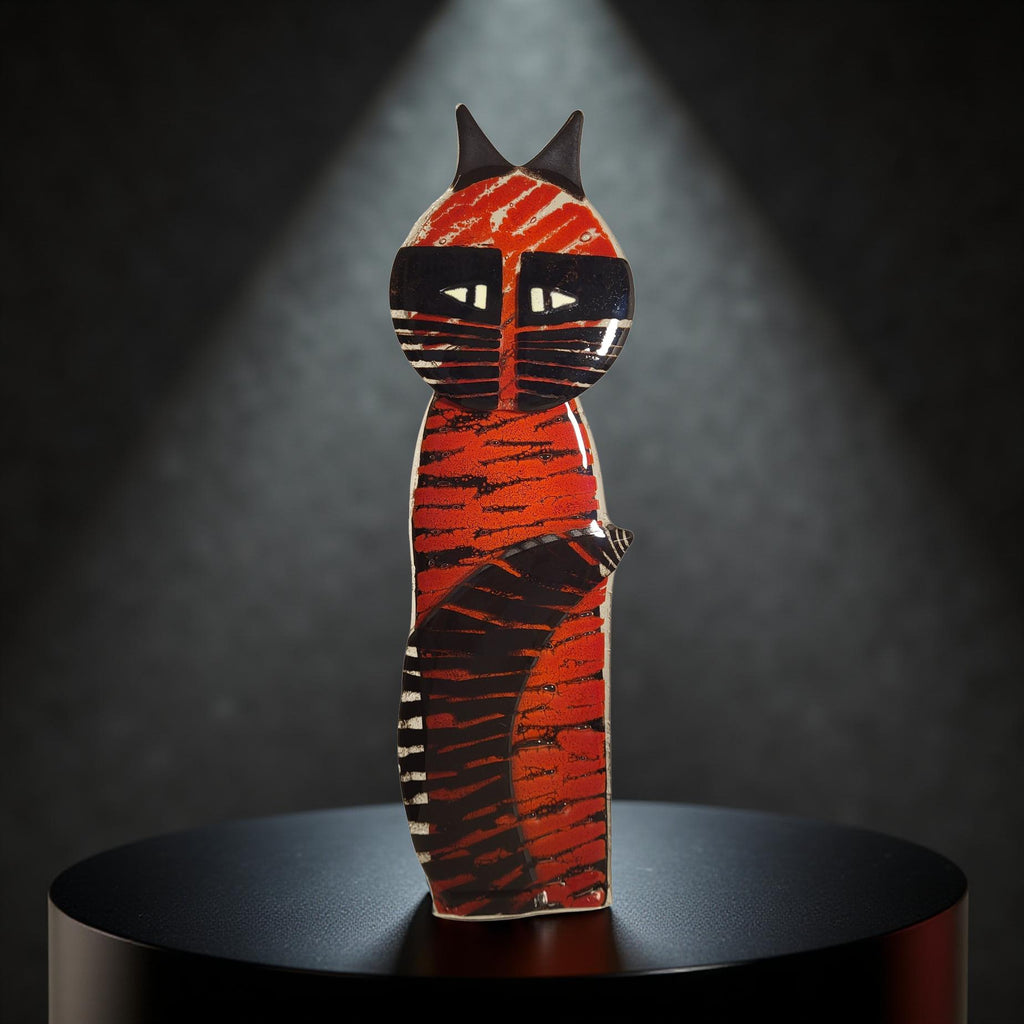 A colorful ceramic cat figurine is displayed on a black pedestal against a dark background.