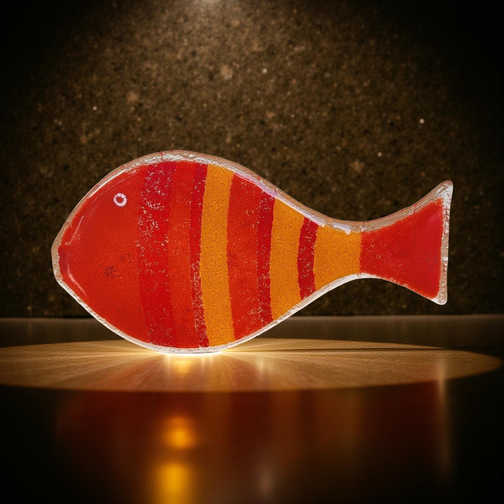 A colorful, abstract fish-shaped object with red and orange stripes is displayed against a dark background.