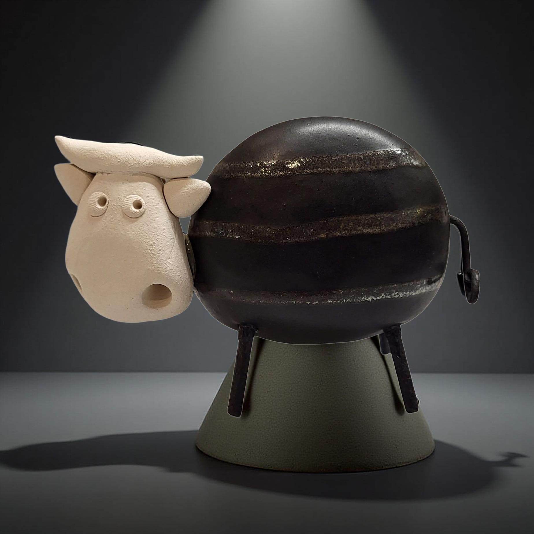 A ceramic sculpture of a cow with a black and white striped pattern, sitting on a gray base and facing to the left.